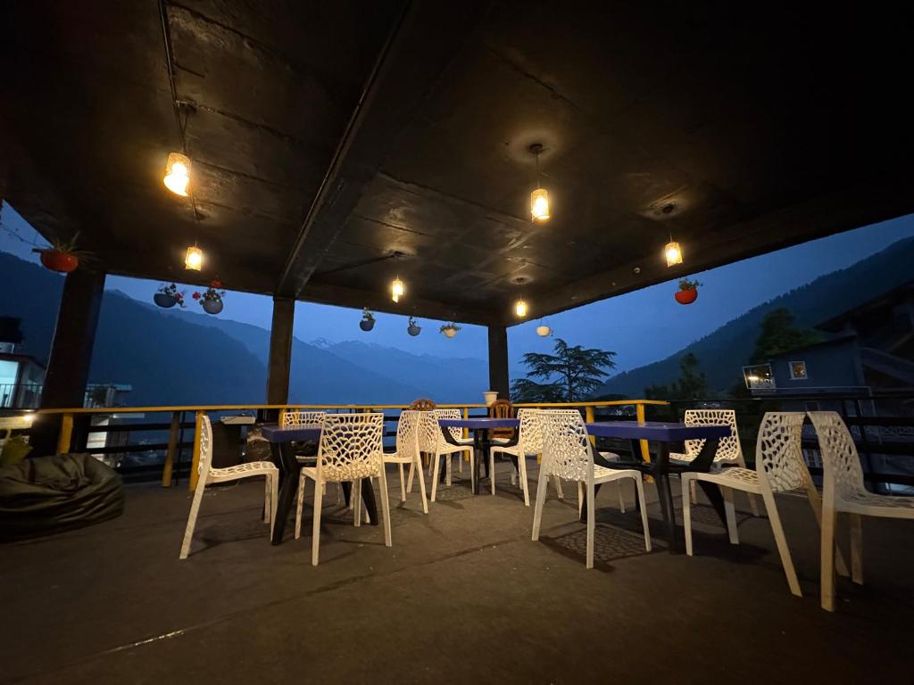 a group of tables and chairs on a deck at night at New Suraj Inn - Nestled near Hadimba Temple ! Rooftop Cafe ! Private Parking in Manāli
