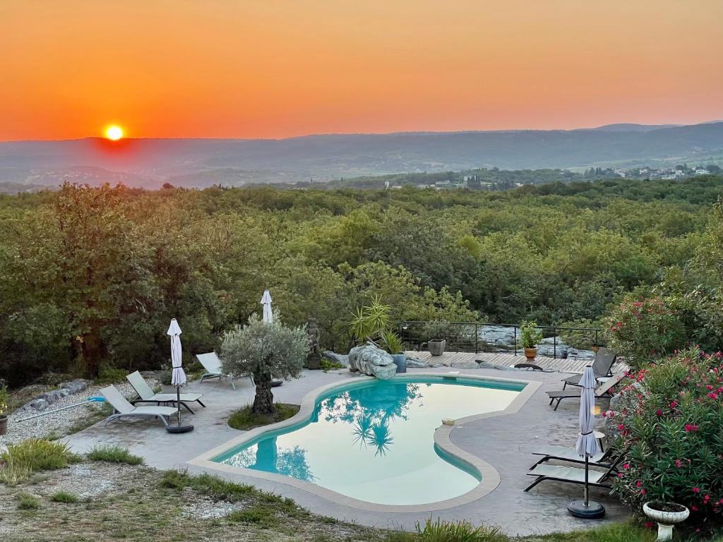 a swimming pool with a sunset in the background at Les Dolines in Balazuc
