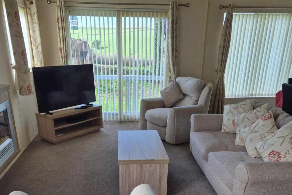 a living room with a couch and a television at 2 Bed Caravan - Sleeps 6 - Pets - Pool - Parking in Newquay