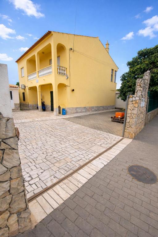a large yellow building with a stone driveway at Vivenda Santos in Albufeira