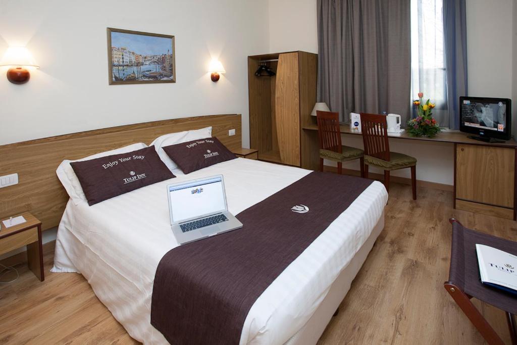 a hotel room with a bed with two laptops on it at Tulip Inn Padova in Padova