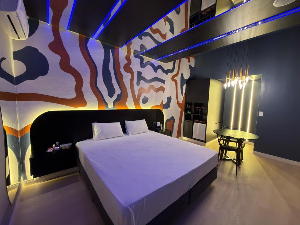 a bedroom with a bed with a painting on the wall at Blue Suítes - motel in Cascavel