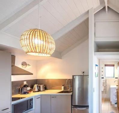 a kitchen with a refrigerator and a chandelier at Hot Tub Seaview Chalet 12 in Waiheke Island