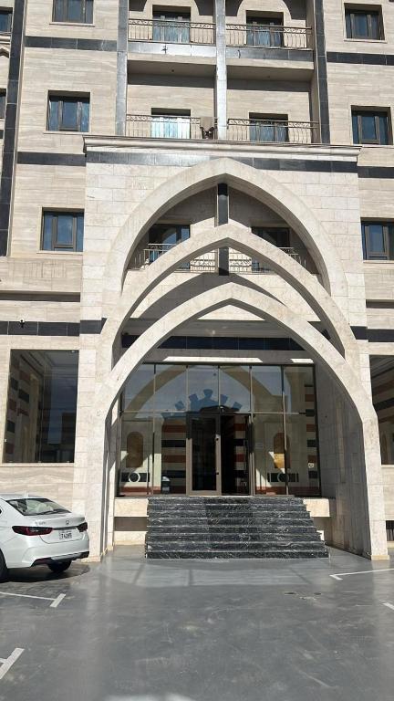 a building with an arch entrance with a car parked in front at Noble Rose Apartment in Kuwait