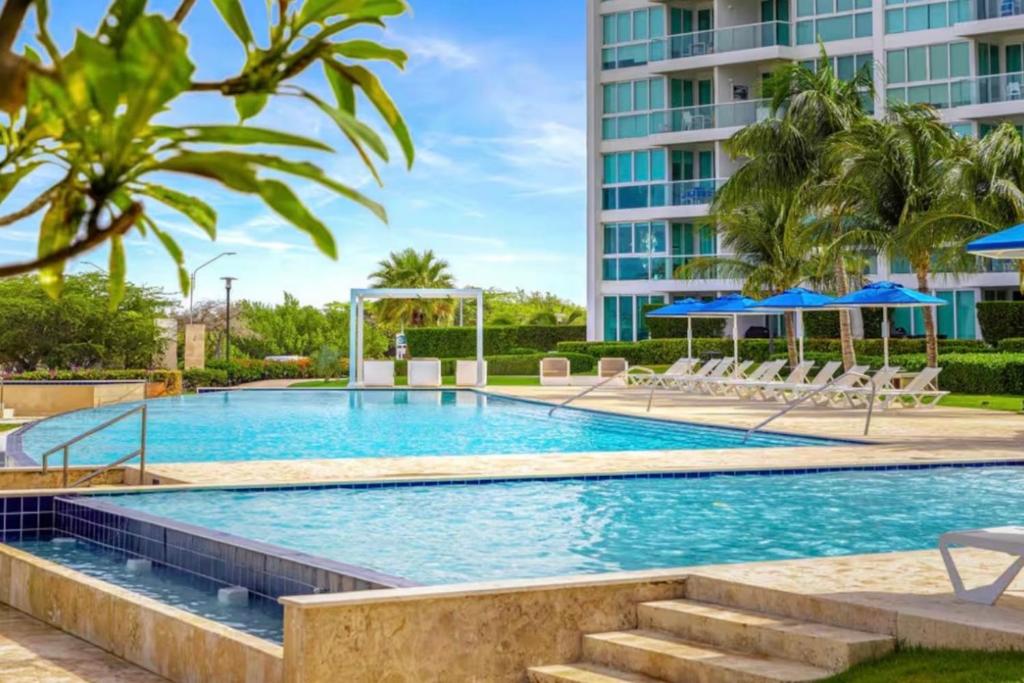 a swimming pool with chairs and umbrellas in a resort at Apartment in paradise on the happy island of ARUBA, beachfront in Savaneta