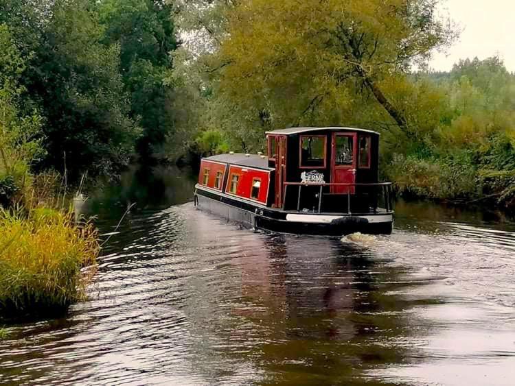 a small boat traveling down a river at The Erne Rambler in Silverhill
