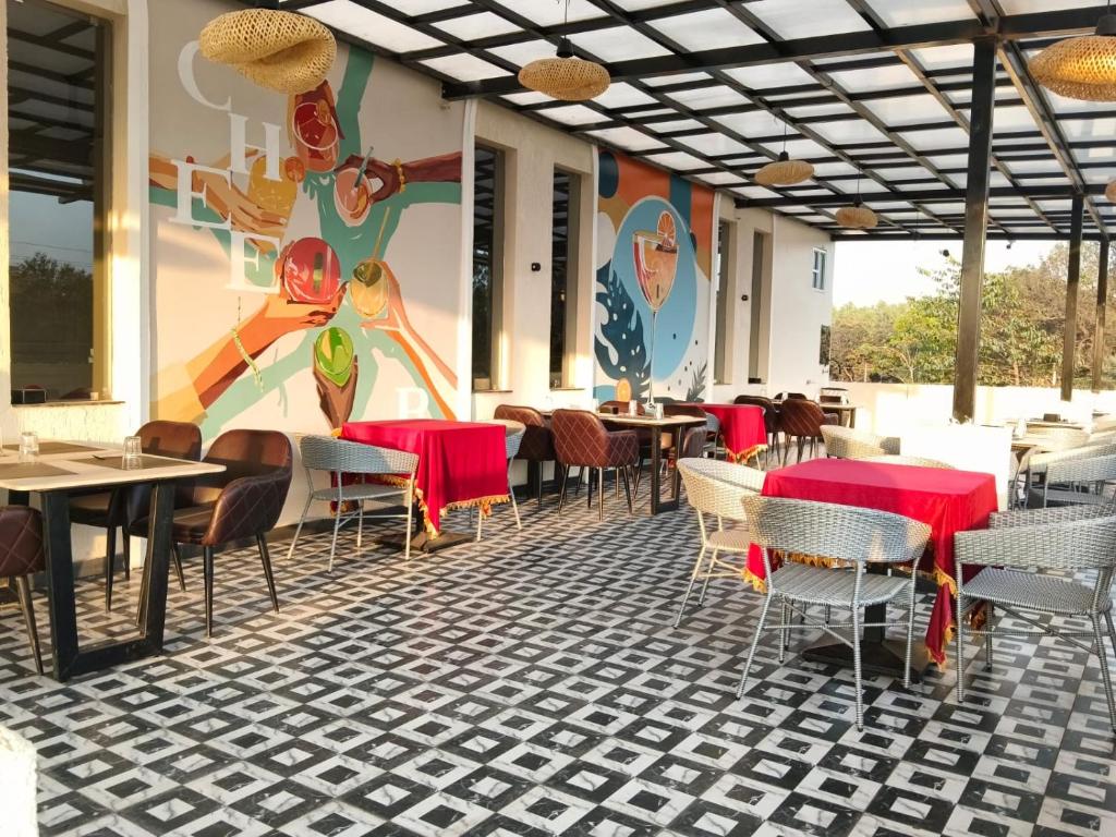a restaurant with tables and chairs and a colorful wall at IR Resorts Mahasamund in Mahāsamund