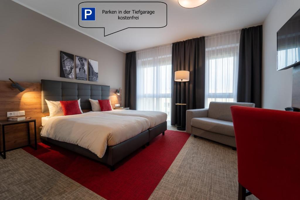 a hotel room with a bed and a chair at Hotel INCLUDiO in Regensburg