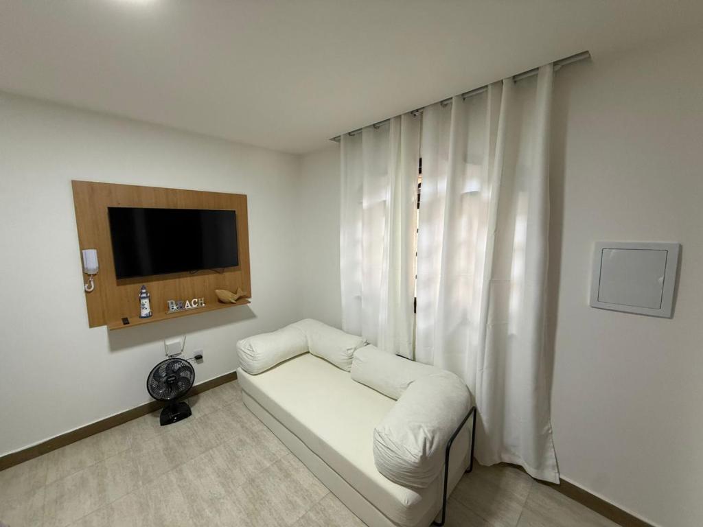 a living room with a white couch and a television at Casa da Dinda 103 in Rio das Ostras