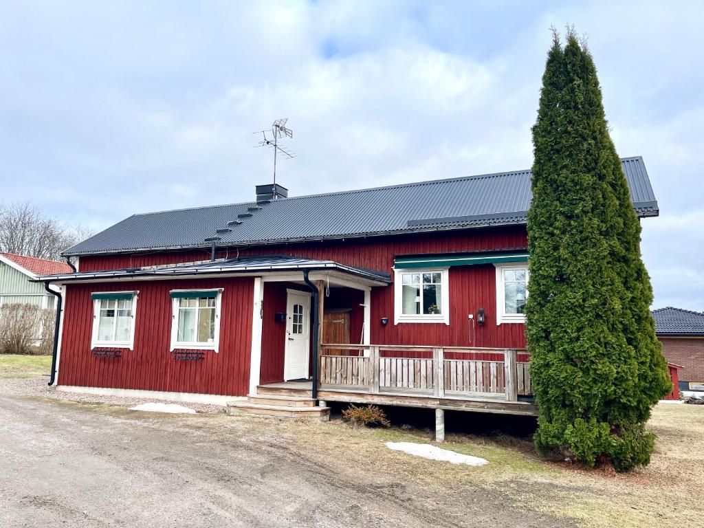 a red house with a tree in front of it at Gästhus i Västanbyn, Sandviken in Sandviken