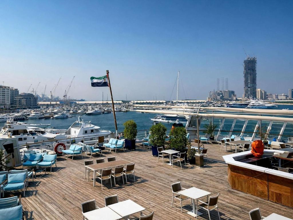 a deck with tables and chairs and a marina with boats at Queen Elizabeth 2 Hotel in Dubai
