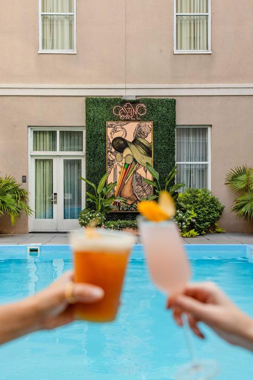 a person holding a drink and a cell phone next to a pool at Hyatt Centric French Quarter New Orleans in New Orleans