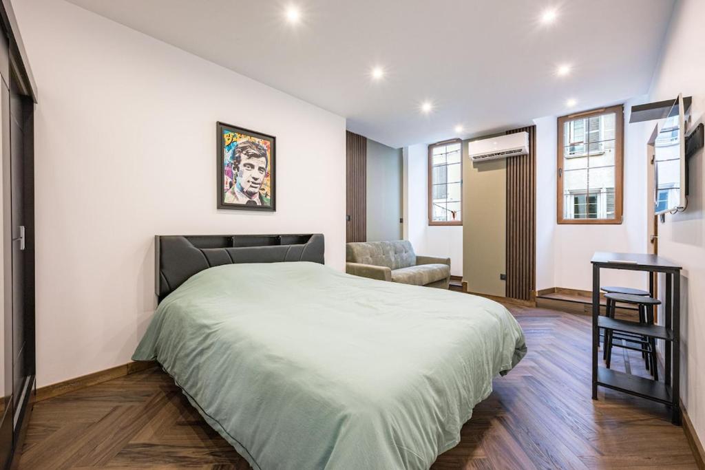 a bedroom with a large bed and a chair at Le Belmondo Grand Studio in Moutiers
