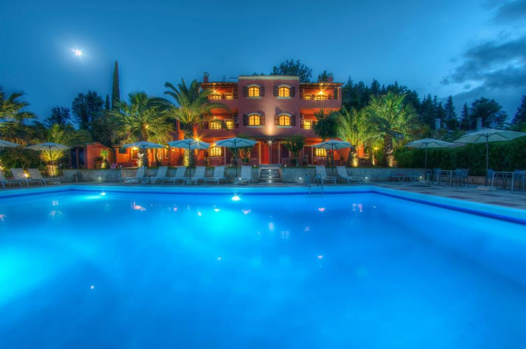 a large swimming pool in front of a house at night at The Palm Garden in Ermones