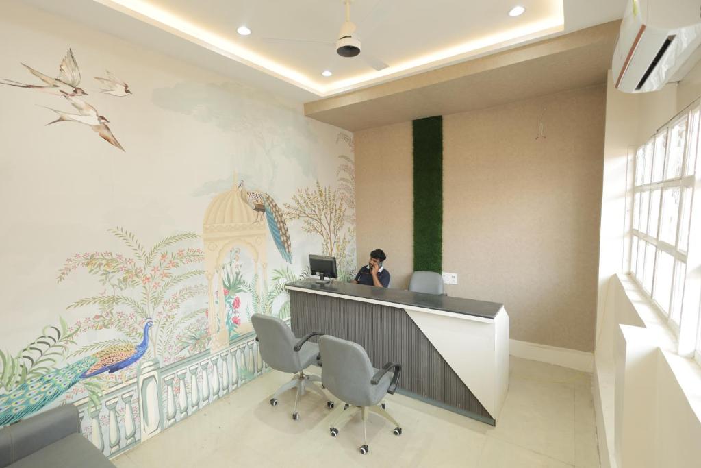 a woman sitting at a desk in an office with a laptop at Hotel Keshav Pride in Dhule