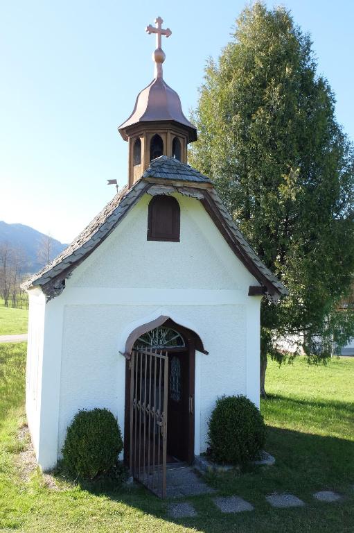 a small white chapel with a cross on top of it at Erlachmühle in Mondsee