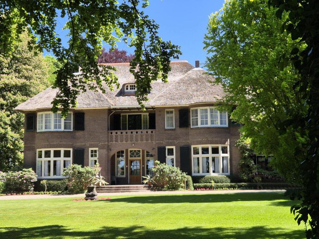 a large brick house with a green lawn at Huize Beukenstein in Lochem