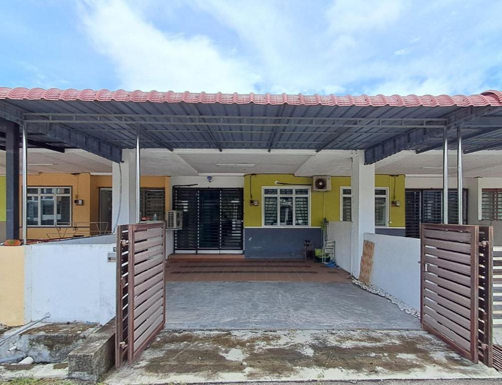 a house with a wooden gate and a yellow house at Homestay nakhoda Sitiawan in Lumut
