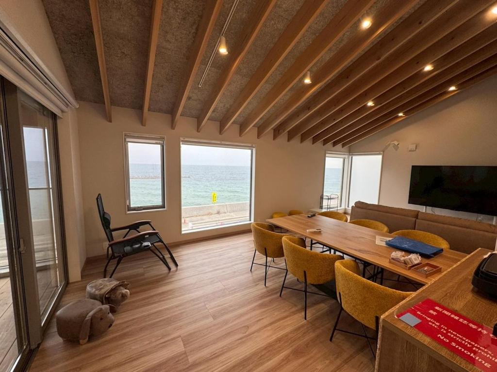 a living room with a table and chairs and the ocean at Laina Kai in Sumoto