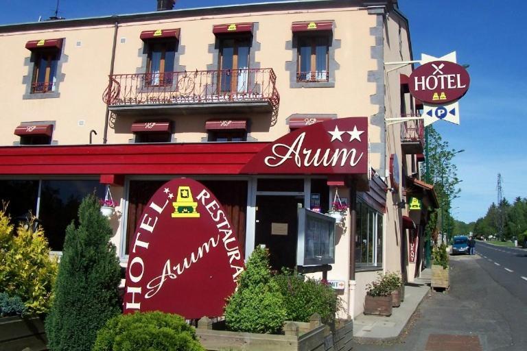 a restaurant with a red sign on the front of a building at Arum in Orcines