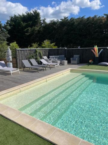 a swimming pool with lounge chairs and chairs next to it at La maison du bois brulée 5 in Villaines-les-Rochers