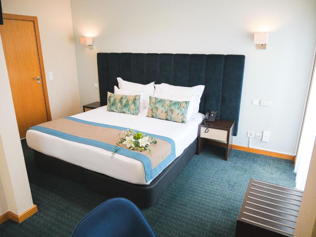 A double-bed room with a tall upholstered headboard, desk and window-side seating area.