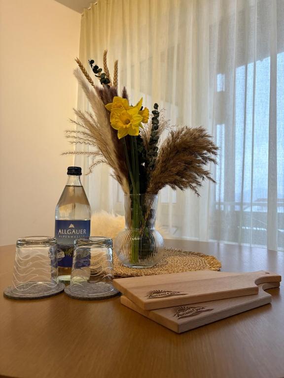 a vase of flowers and a bottle of water on a table at AuszeitOase inkl Oberstaufen Plus Karte in Oberstaufen