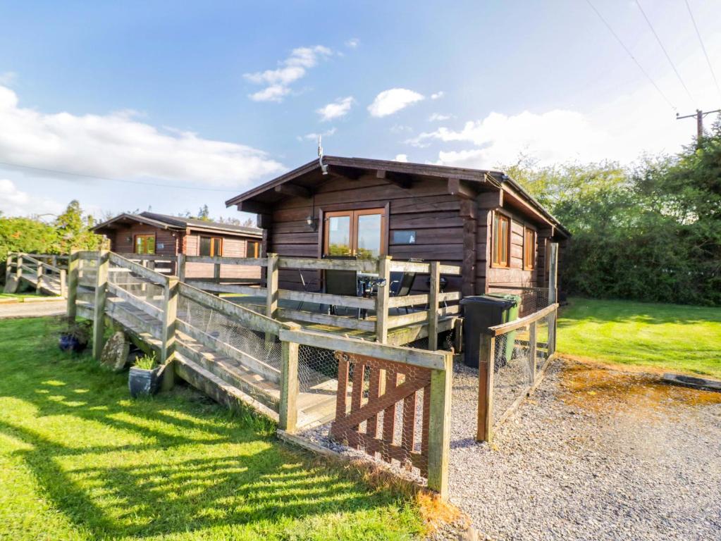 a wooden cabin with a fence in front of it at Primrose Lodge in Evesham