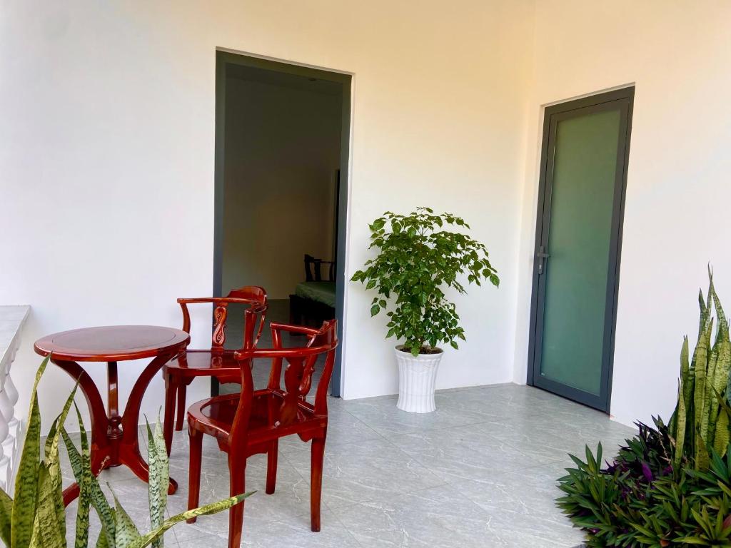 a patio with two red chairs and a table at Ocean Bungalow in Phú Quốc