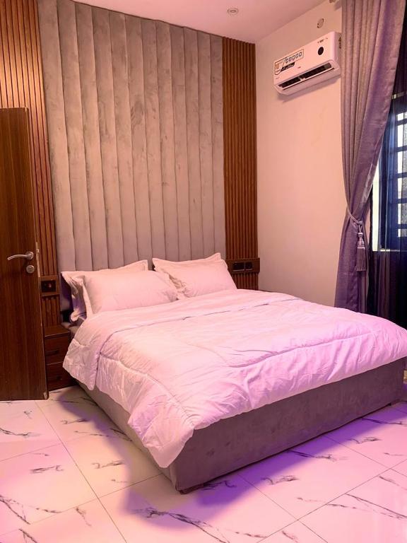 a bedroom with a large bed with pink sheets at Ehi-Mega Luxury Hotel and Apartment in Abuja