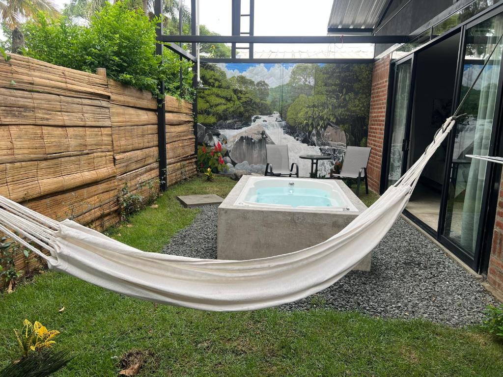 a hammock in a backyard with a hot tub at Cabaña El Anhelo Bosque in Ginebra