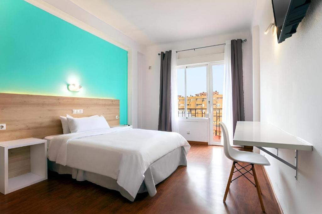 a bedroom with a bed and a desk and a window at BLUESEA Torremolinos Centro in Torremolinos