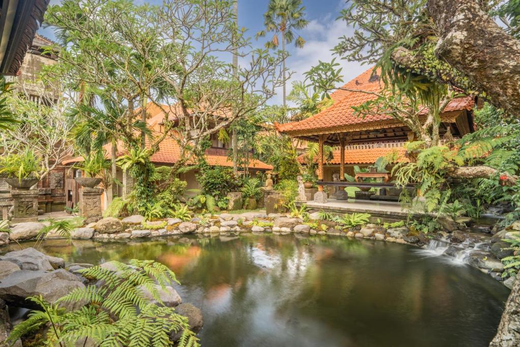 a garden with a pond in front of a house at Aksara Ubud in Ubud