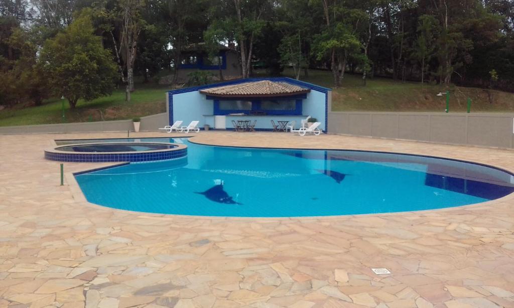 a large blue pool with a house in the background at Hotel Pousada Gurupiá in Serra Negra