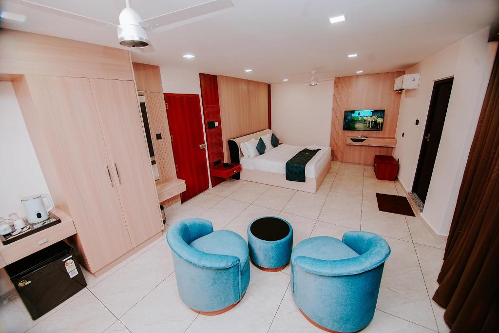 a room with two blue chairs and a bed at Empire Suites in Erāttupetta