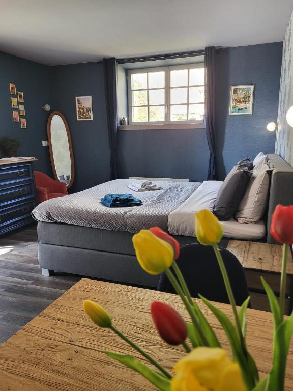a bedroom with a bed with flowers in the foreground at Chambre d'hôtes l'Heure Bleue in Saint-Alvère