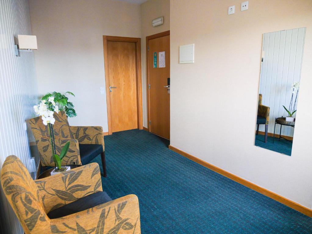 A small hotel waiting area with patterned armchairs, a mirror and wood doors.