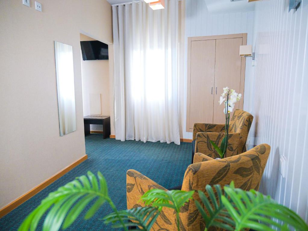 A compact sitting area with armchairs, a curtained window, television and wardrobe-style storage.