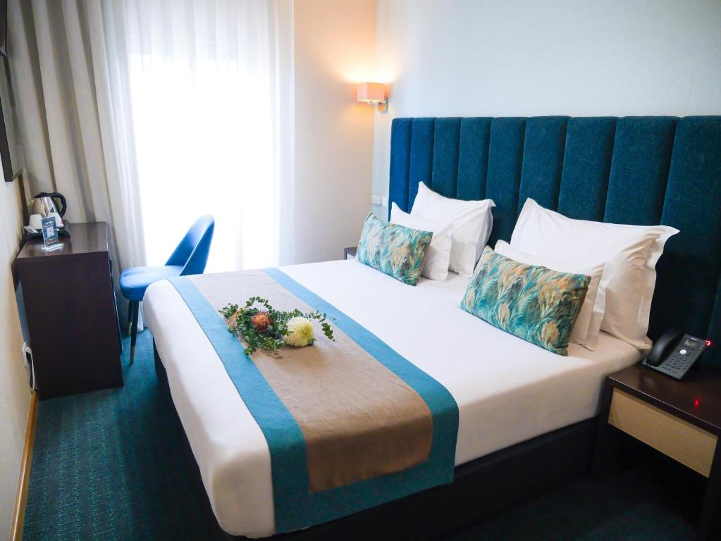 A double room with a teal upholstered headboard, desk, kettle and bedside telephone.