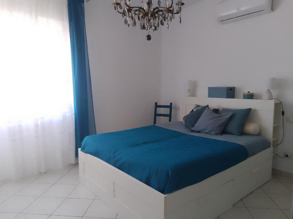 a bedroom with a bed with blue sheets and a chandelier at Casa AnnaMarea in San Vincenzo
