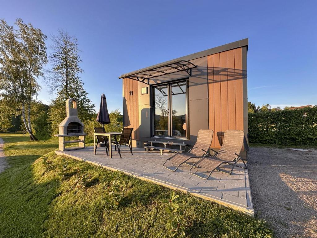 a tiny house with a patio and a table and chairs at Feriendorf Seeblick - Tiny Nr 11 in Neunburg vorm Wald