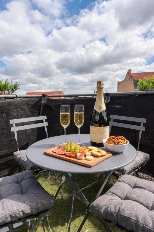a table with a bottle of wine and two glasses at L'Écrin Marguerite - Strasbourg-CMCO-Zénith-Espace Européen de l'Entreprise in Schiltigheim