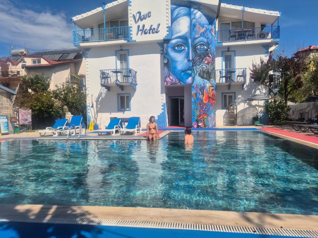 a woman sitting in a swimming pool in front of a building at Dove Apart Hotel in Fethiye