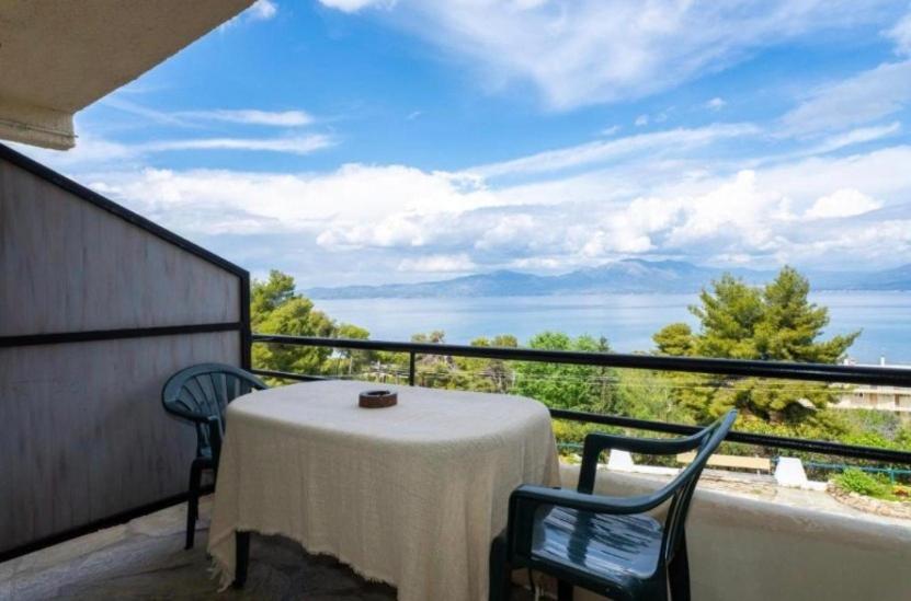 a table and chairs on a balcony with a view of the ocean at GM View Oropos in Oropos