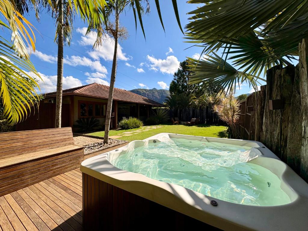 a hot tub in a backyard with palm trees at Chalet Monte Boa Vista - Aconchego na Serra com Hidromassagem Exclusiva in Teresópolis