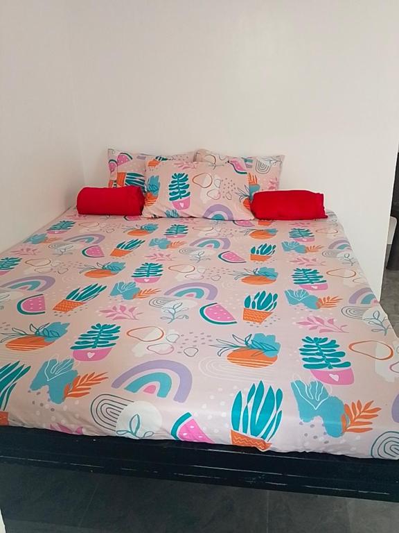a bed with a colorful comforter and pillows on it at Llave transient 2 in Nasugbu