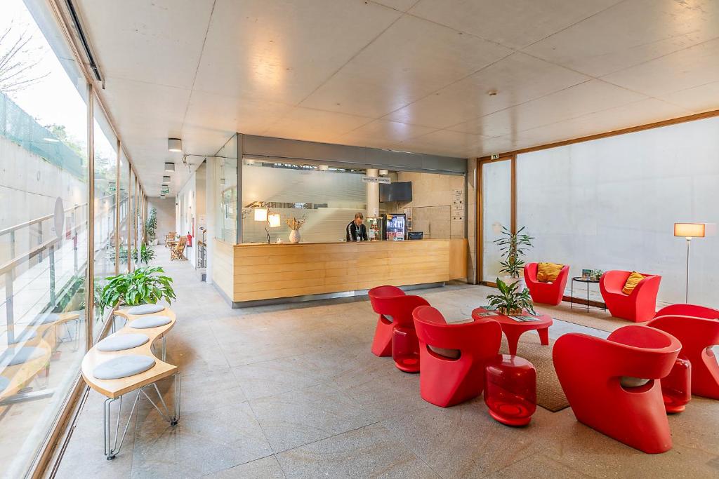 a lobby with red chairs and tables and a counter at HI Ponte de Lima - Pousada de Juventude in Ponte de Lima