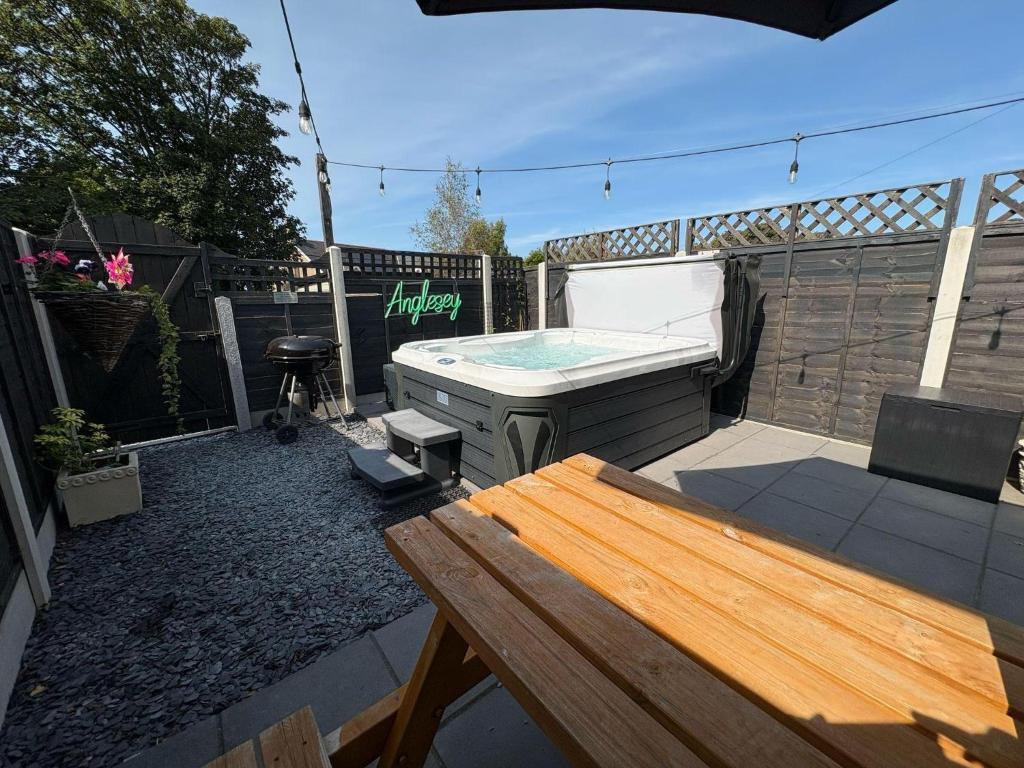 a small backyard with a hot tub and a table at Gwens House in Brynsiencyn