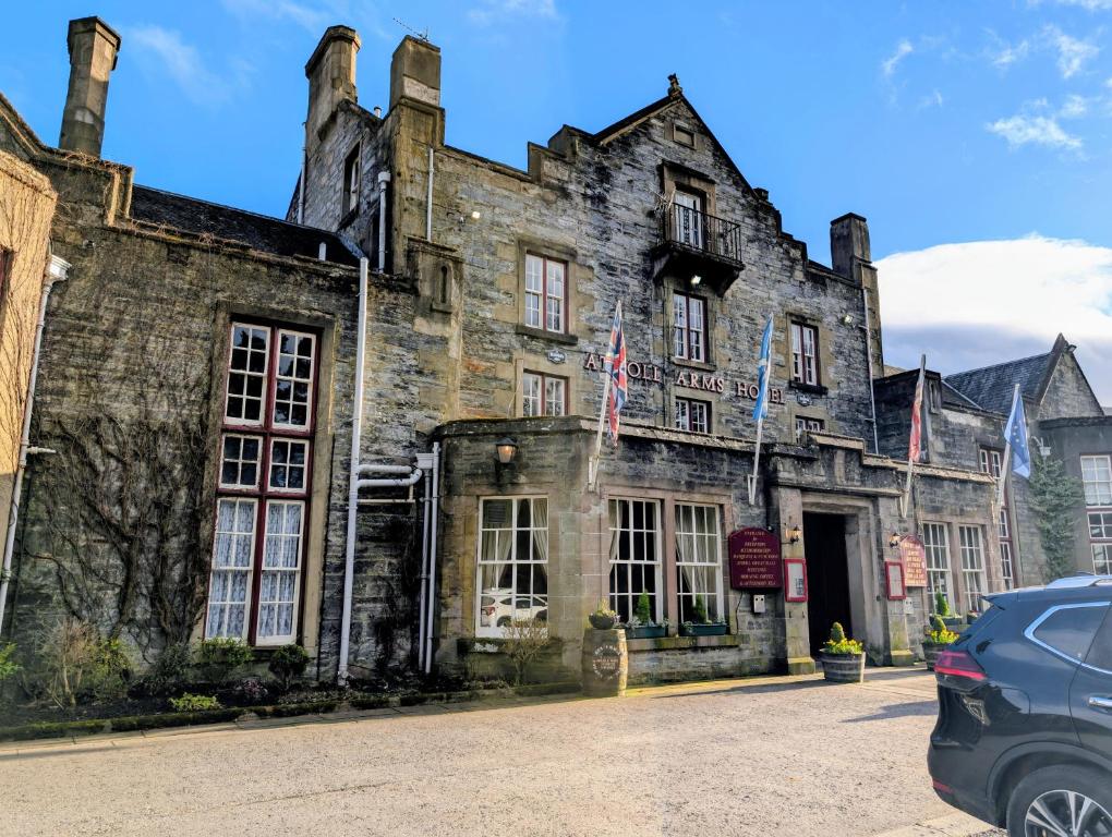 an old stone building with american flags on it at Atholl Arms in Blair Atholl