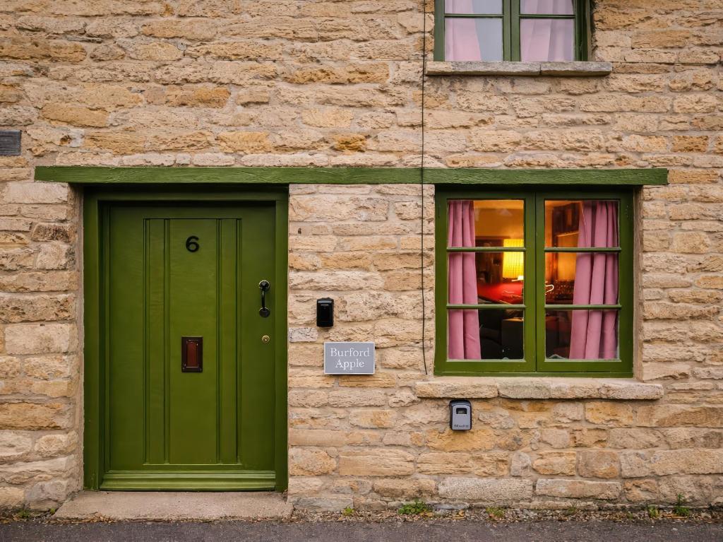 a green door and a window on a brick building at Burford Apple in Burford